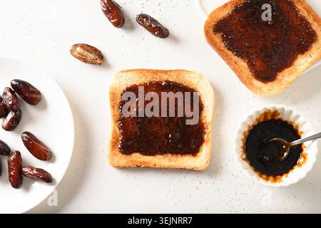 Fresh crispy toasts with dates syrup without sugar on white table. Healthy breakfast without sugar. Stock Photo