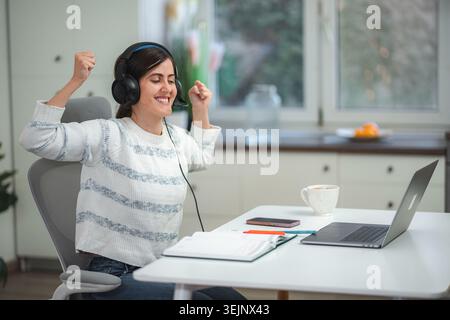 Happy woman celebrating success while working from home Stock Photo
