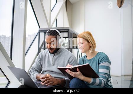Diverse colleagues collaborating, focused on laptop and notebook Stock Photo