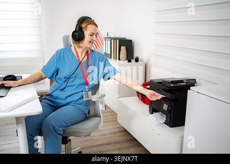 Female nurse working in office multitasking and using printer Stock Photo