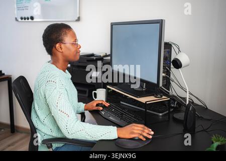 Black woman working from home using computer and keyboard Stock Photo