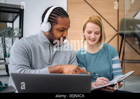 Diverse colleagues collaborating on project, man pointing at laptop Stock Photo