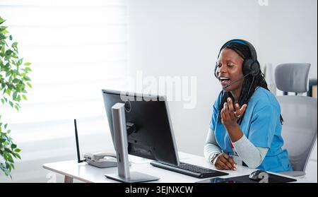 Female medical professional communicating, offering remote healthcare consultation from office Stock Photo