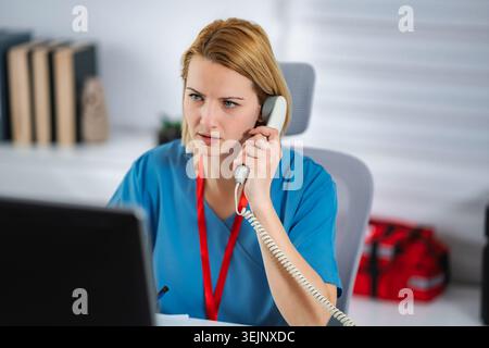 Female nurse talking on phone while working at desk Stock Photo