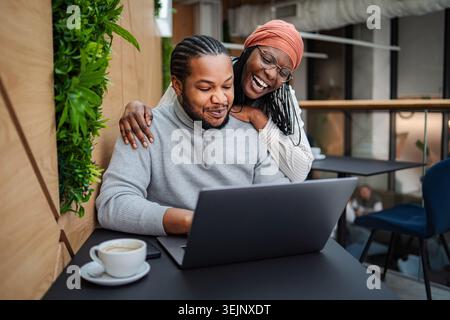 Black couple laughing, working, and connecting in a modern cafe Stock Photo