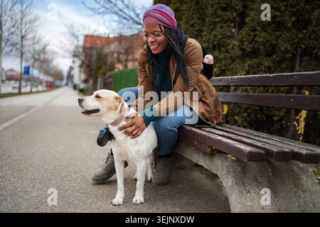Young adult woman relaxing on park bench with pet dog Stock Photo