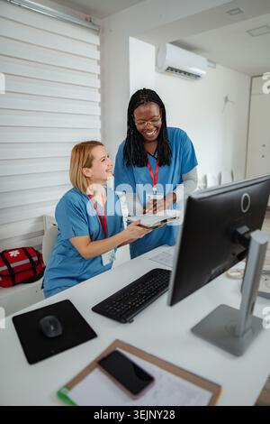 Two nurses smiling, working together at a reception desk in a clinic Stock Photo