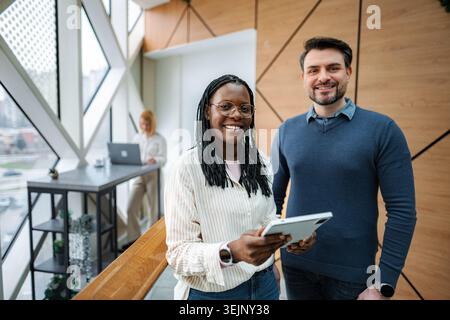 Diverse business professionals smiling, collaborating in modern office Stock Photo