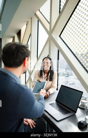 Coworkers exchanging data using digital tablet during business meeting Stock Photo