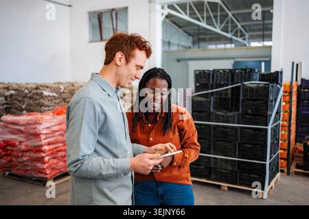 Diverse colleagues managing warehouse inventory using digital tablet Stock Photo