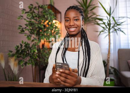 Young black woman holding smartphone smiling at camera Stock Photo