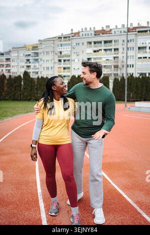 Diverse couple walking and talking on running track Stock Photo