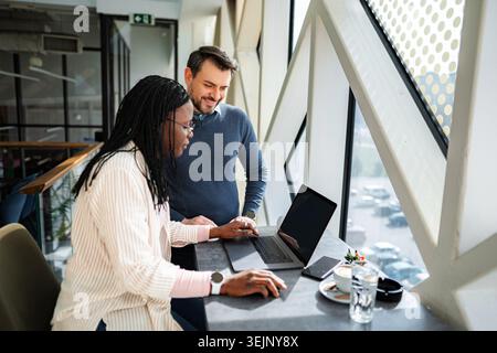 Diverse business professionals collaborating on laptop in modern office Stock Photo
