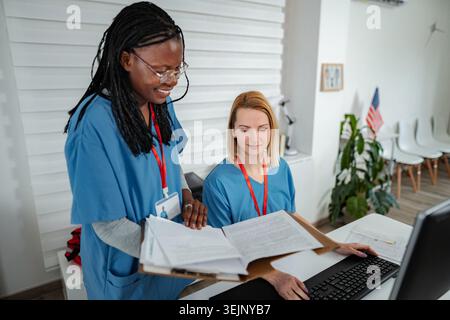 Diverse nurses collaborating on medical records in clinic Stock Photo