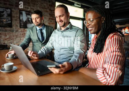 Diverse business team collaborating on laptop in cafe Stock Photo