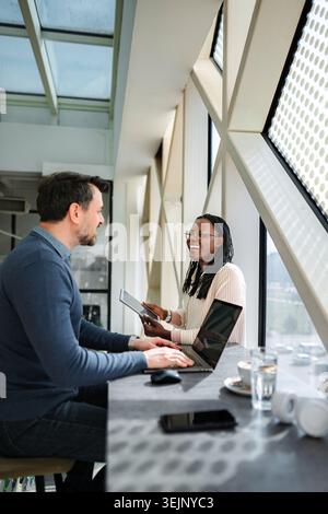 Diverse business professionals collaborating on laptop and tablet Stock Photo