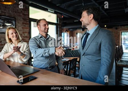 Businessmen shaking hands making agreement at bar Stock Photo