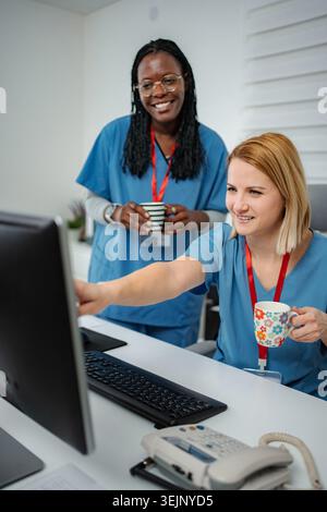 Nurses collaborating looking at computer screen in clinic Stock Photo