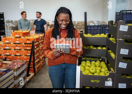 Woman worker using tablet checking fruit in warehouse Stock Photo