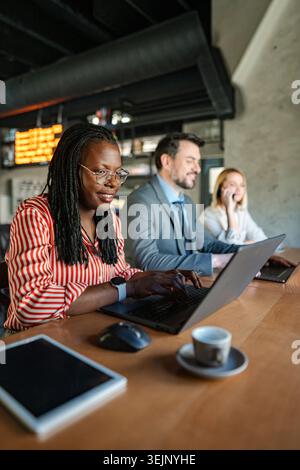 Diverse business professionals working on laptops in a modern cafe Stock Photo