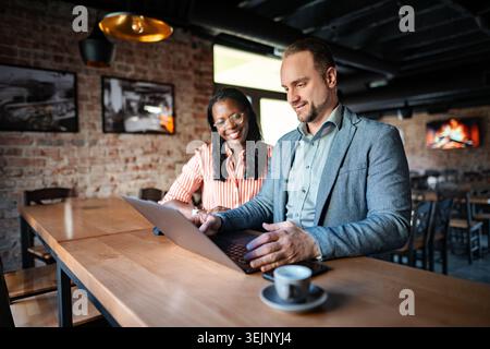 Diverse colleagues collaborating using laptop during coffee break Stock Photo