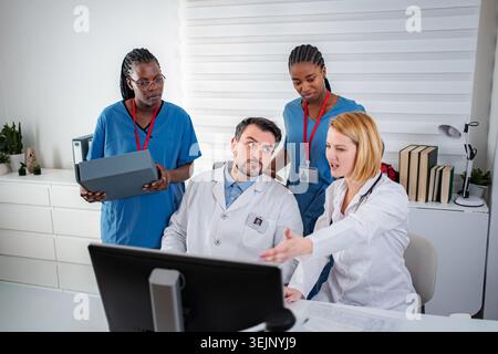 Medical team collaborating and discussing patient data on computer Stock Photo