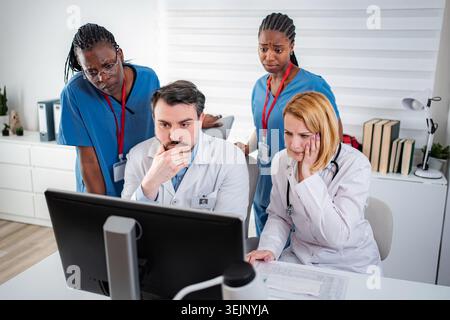 Medical team collaborating on urgent problem using computer Stock Photo