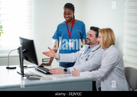 Healthcare professionals working together, discussing patient data on a desktop computer Stock Photo