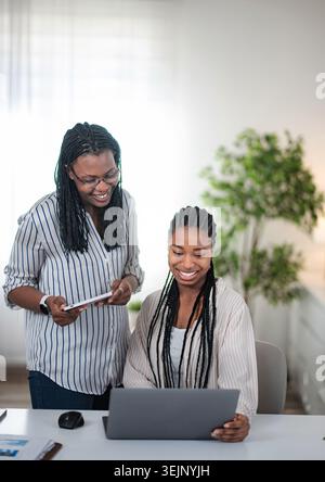 African American businesswomen collaborating on tablet and laptop in office Stock Photo