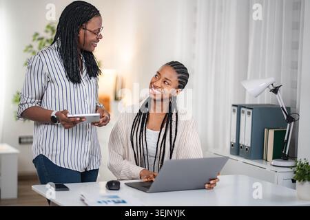 Diverse business women collaborating on laptop and digital tablet Stock Photo