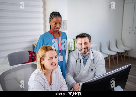 Multi-ethnic medical professionals working together reviewing patient data on a computer Stock Photo