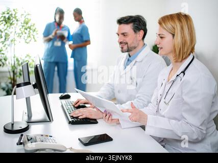 Medical team collaborating and checking documents on computer Stock Photo