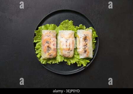 Vietnamese spring rolls with shrimp in center of black table. Asian cuisine. Stock Photo