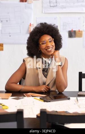 African American woman checking plans and samples at studio table using tablet after client brief. Design, architecture, interior, creative, workspace Stock Photo