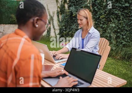 Coworkers using laptops and working outdoor in the garden Stock Photo