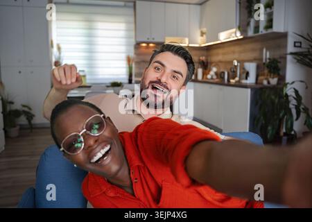 Young Couple Taking a Playful Selfie on the Couch at Home Stock Photo