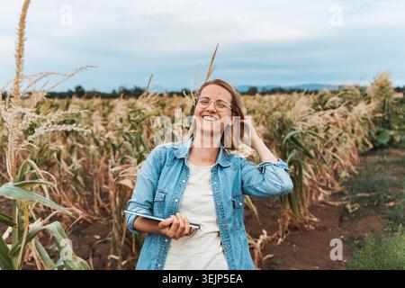 Farmer smiling and holding tablet in corn field Stock Photo