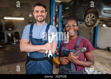 Two happy mechanics smiling at camera in auto repair shop Stock Photo