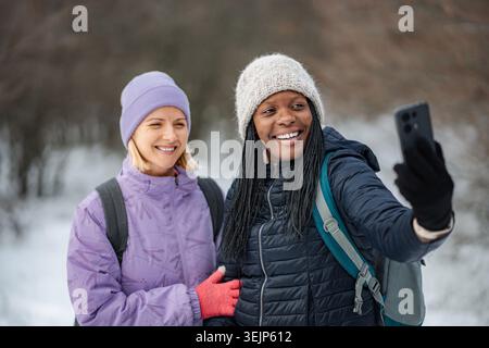 Diverse friends taking selfie enjoying winter hiking together Stock Photo