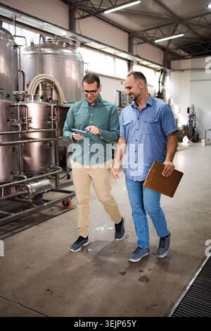 Brewery workers discussing production using tablet technology Stock Photo