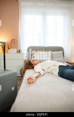 Woman relaxing on bed after travel exhaustion Stock Photo
