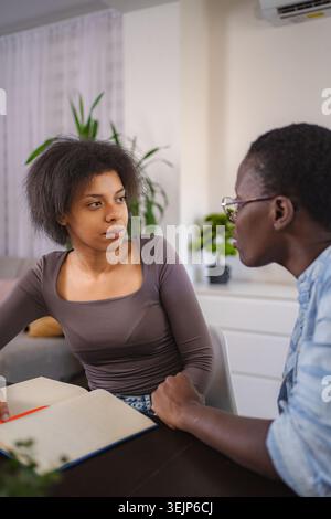 Young students studying together at home, taking notes and discussing Stock Photo