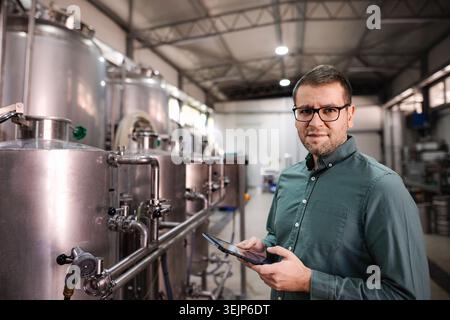 Man managing quality control and production in a modern brewery using a digital tablet Stock Photo
