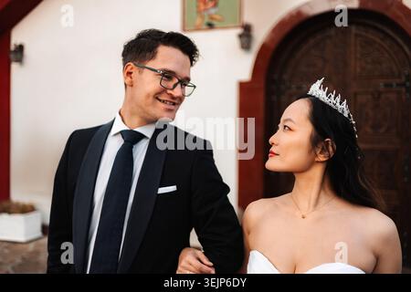 Interracial wedding couple looking at each other smiling Stock Photo