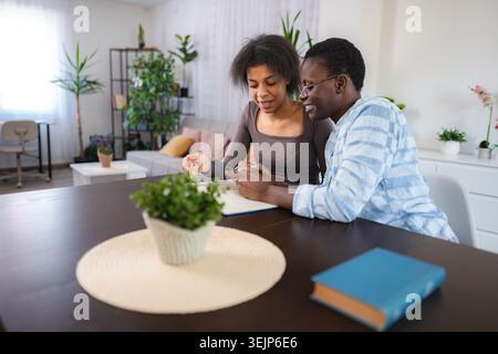 Young couple using mobile phone and smiling at home Stock Photo