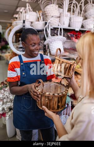 Florist showing wooden flower baskets to customer in flower shop Stock Photo