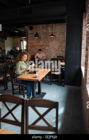 Young woman using smartphone in a modern cafe Stock Photo