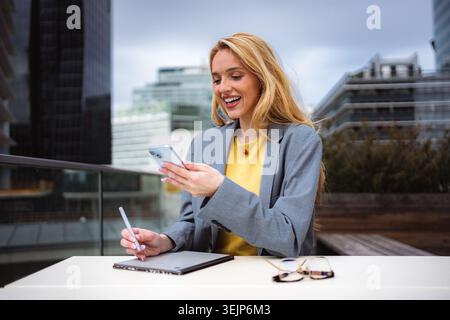 Young businesswoman using smartphone and drawing tablet outdoors Stock Photo