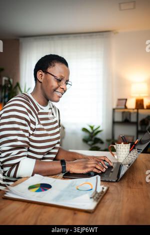 African American woman working remotely on laptop at her home office Stock Photo