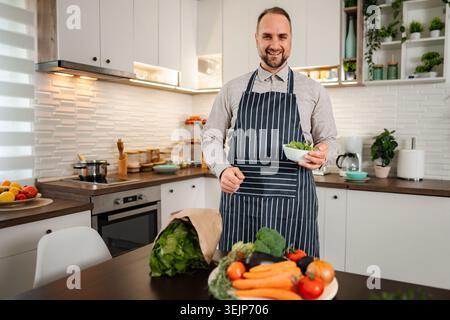 Man preparing healthy meal with fresh vegetables in kitchen Stock Photo